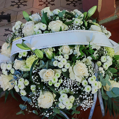 Grand coussin de deuil composé de fleurs blanches avec lys et ruban